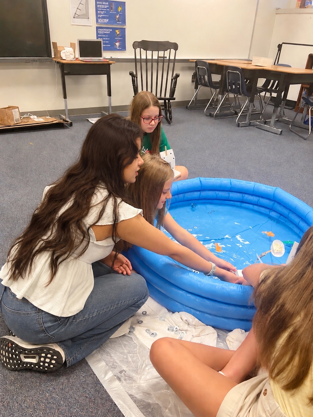 Me with Camp Invention campers testing boat prototypes in a small pool